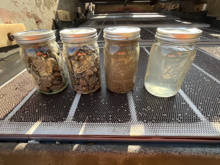 Four jars showing stages of hydro excavation waste recycling